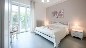 A bedroom with a bed, bedside tables, a chair, a radiator, and a balcony.