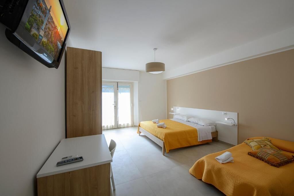 A hotel room with a bed, a desk, a television, and a window.