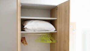 A wooden wardrobe with shelves, a hanging space, and a small table.