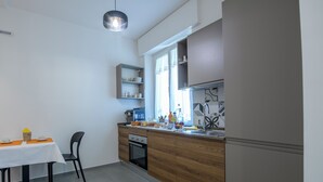 A compact kitchen with a built-in oven, a coffee machine, and a window providing natural light.
