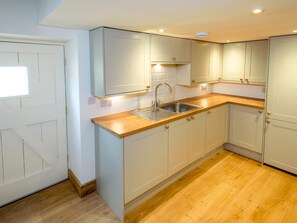 Une cuisine moderne avec des armoires blanches, un plan de travail en bois et un évier en acier inoxydable.