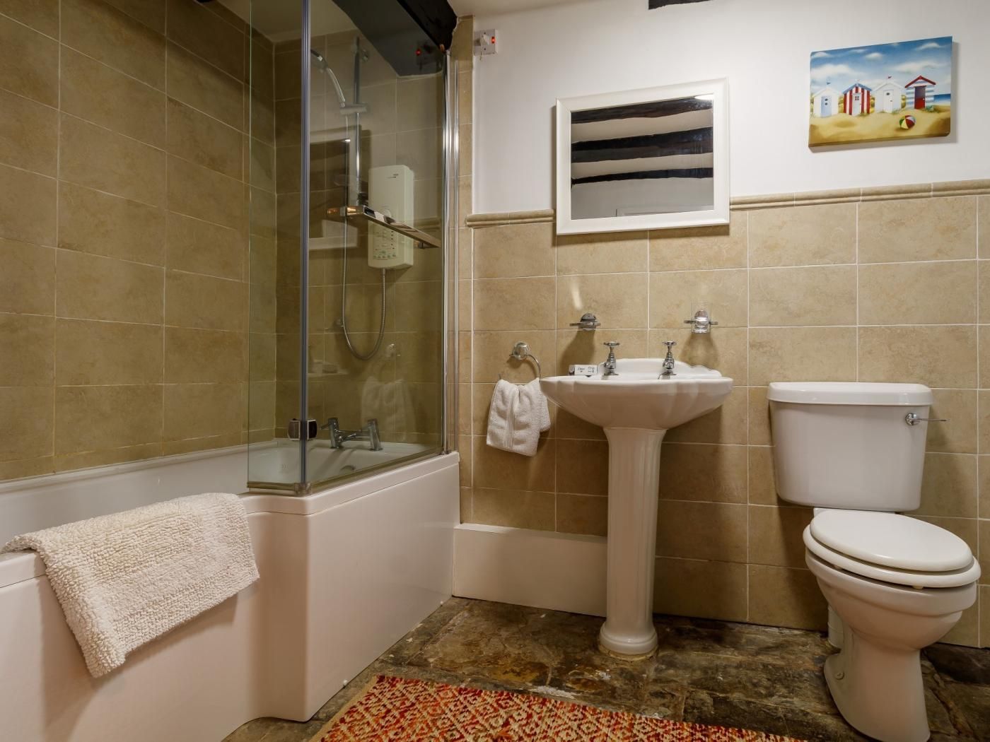 Une salle de bain avec une douche à parois de verre, un lavabo sur colonne, des toilettes et une serviette accrochée au mur.