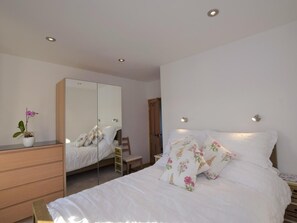 A bedroom with a bed, a dresser, a mirror, and a nightstand.