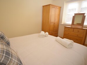 A bedroom with a bed, a wooden wardrobe, and a window with blinds. - 1 Bed in North Walsham (oc-49722) (Worstead)