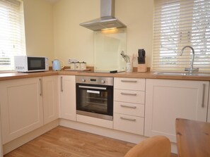 A kitchen with a microwave, oven, and sink. - 1 Bed in North Walsham (oc-49722) (Worstead)