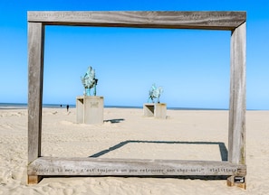 Ein hölzerner Rahmen mit zwei bronzenen Statuen, die einen Reiter an einem sandigen Strand zeigen.