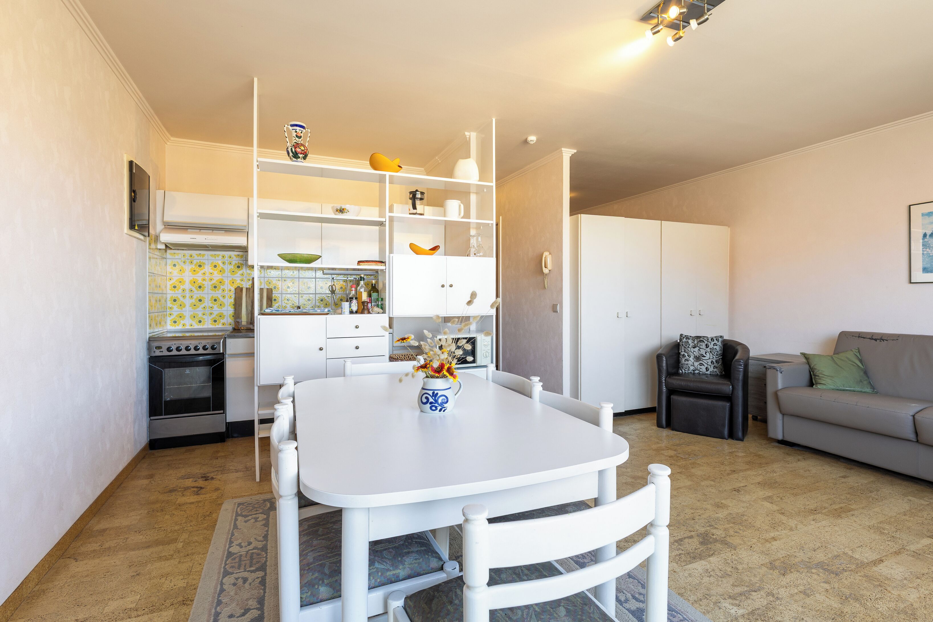 Un espacio habitable compacto con una mesa de comedor, sillas, un sofá y una cocina equipada con horno y refrigerador.