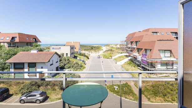 Ein Balkon mit Blick auf einen Strand, einen Parkplatz und Gebäude mit roten Dächern.