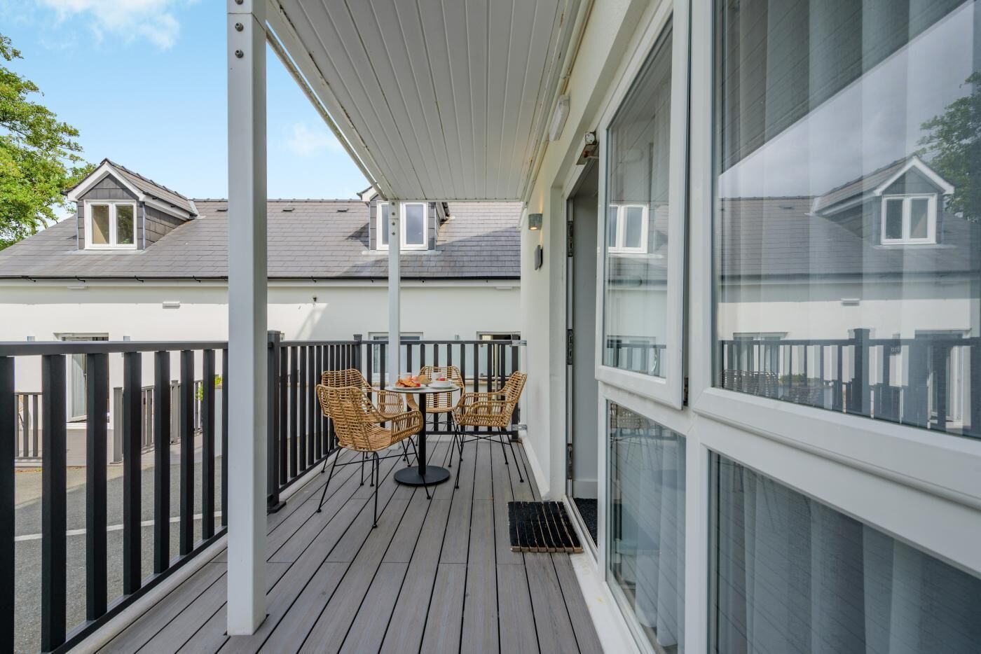 A balcony with a table and chairs, a railing, and a view of neighboring houses.