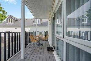 Ein Balkon mit Tisch und Stühlen, einem Geländer und Blick auf benachbarte Häuser.