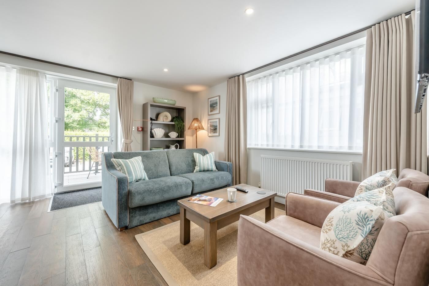 Una sala de estar con sofá, sillón, mesa de centro y estantería.