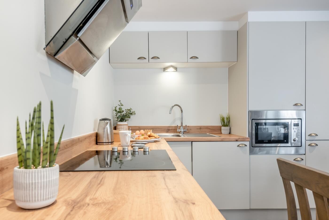 Een moderne keuken met een inbouwoven, roestvrijstalen apparatuur en een houten aanrecht.