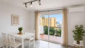 Eine moderne Wohnung mit Essbereich, einem Balkon mit Blick auf Gebäude und Palmen sowie einer Topfpflanze.