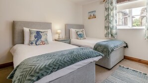 A bedroom with two beds, a window with curtains, a bedside lamp, and a painting on the wall. - 2 Bed in Wedmore (oc-51339) (Middle Stoughton)