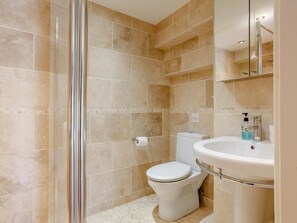 Un bagno con box doccia in vetro, un water e un lavandino con uno specchio sopra.