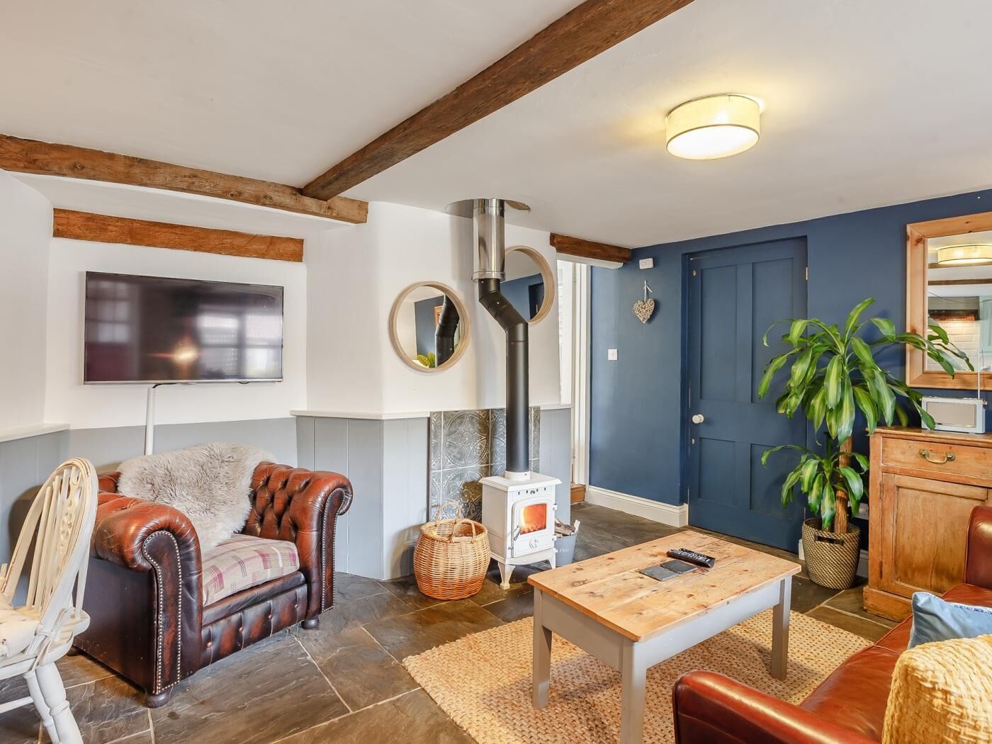 Ein Wohnzimmer mit Kamin, Fernseher, Holztisch und blauer Tür.