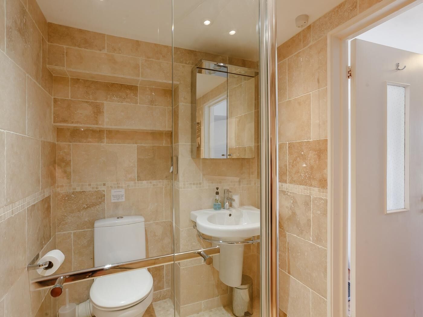 A bathroom with a glass shower enclosure, a white sink, and a toilet.