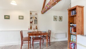 Zona pranzo con tavolo e sedie in legno, una libreria e un ripiano decorativo con diversi oggetti.