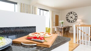 Eine moderne Küche mit Holzarbeitsplatte, einer Pizza auf einem Schneidebrett und einem Essbereich mit Stühlen und einem Tisch.