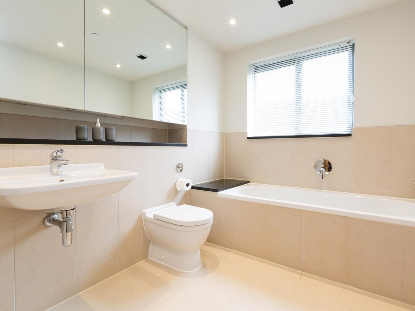 A modern bathroom with a sink, toilet, and bathtub.