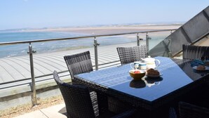 Ein Esstisch mit Stühlen und Blick auf Strand und Meer.