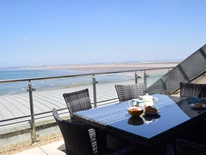 A dining table with chairs and a view of the beach and ocean. - 3 Bed in Bideford (oc-52079) (Westward Ho!)