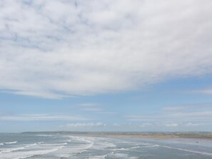 A coastal landscape with a beach, ocean, and a distant shoreline under a cloudy sky. - 3 Bed in Bideford (oc-52079) (Westward Ho!)
