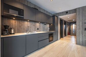 Una cocina moderna con horno empotrado, cafetera y microondas.
