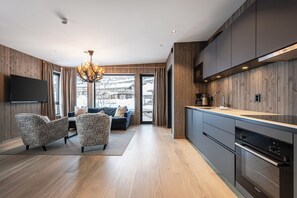 Eine moderne Küche mit dunklen Schränken, einem Einbauofen und einem großen Fenster.