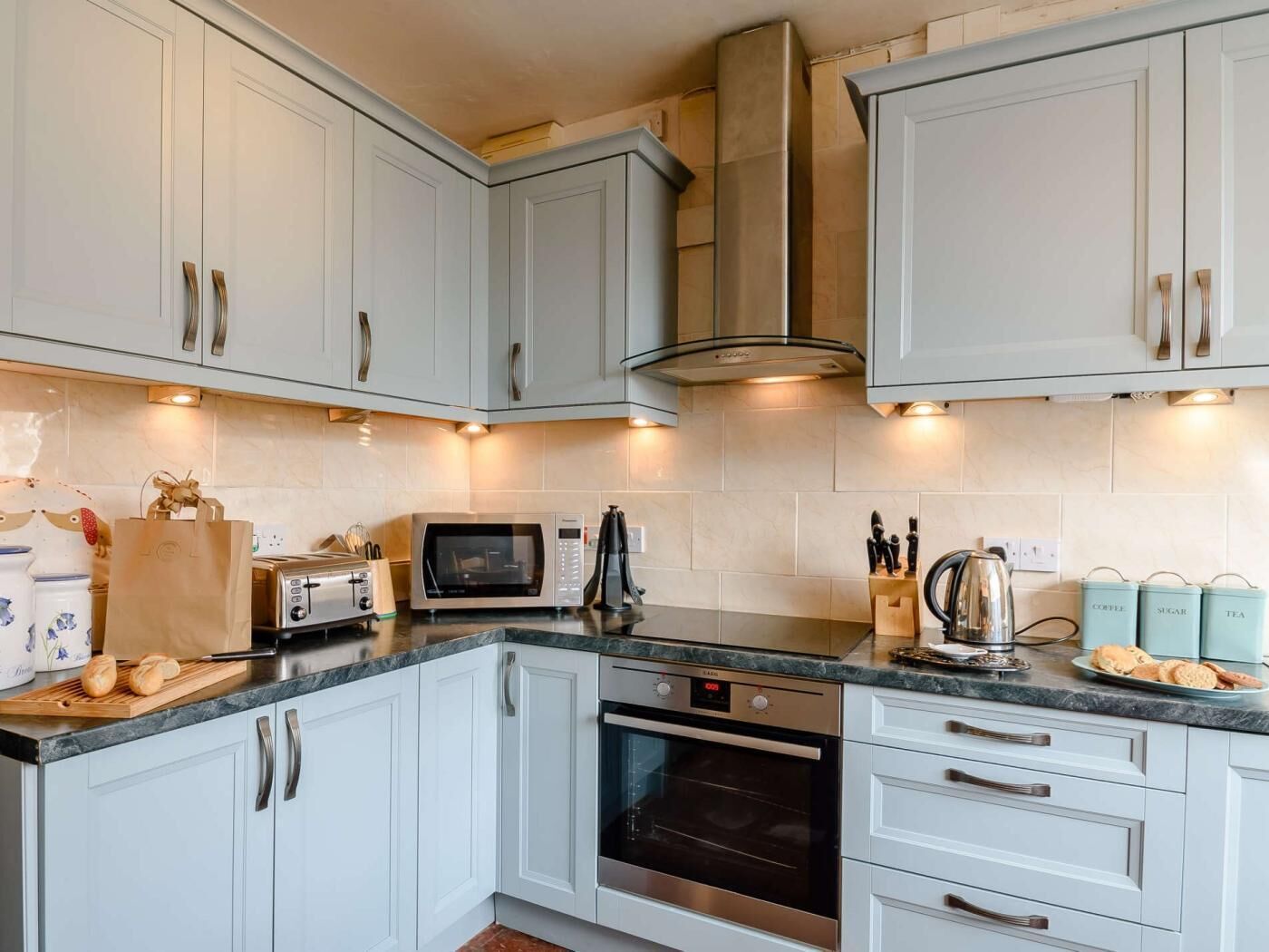 A modern kitchen with white cabinets, stainless steel appliances, and a built-in oven.
