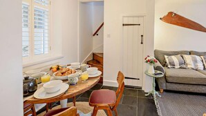 Un comedor con una mesa dispuesta para el desayuno, un sofá y una escalera que lleva a otra habitación.