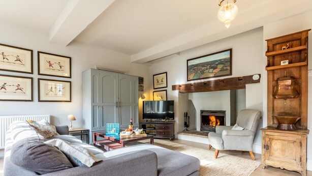 Ein Wohnzimmer mit Sofa, Fernseher, Kamin und Kunstwerken an den Wänden.