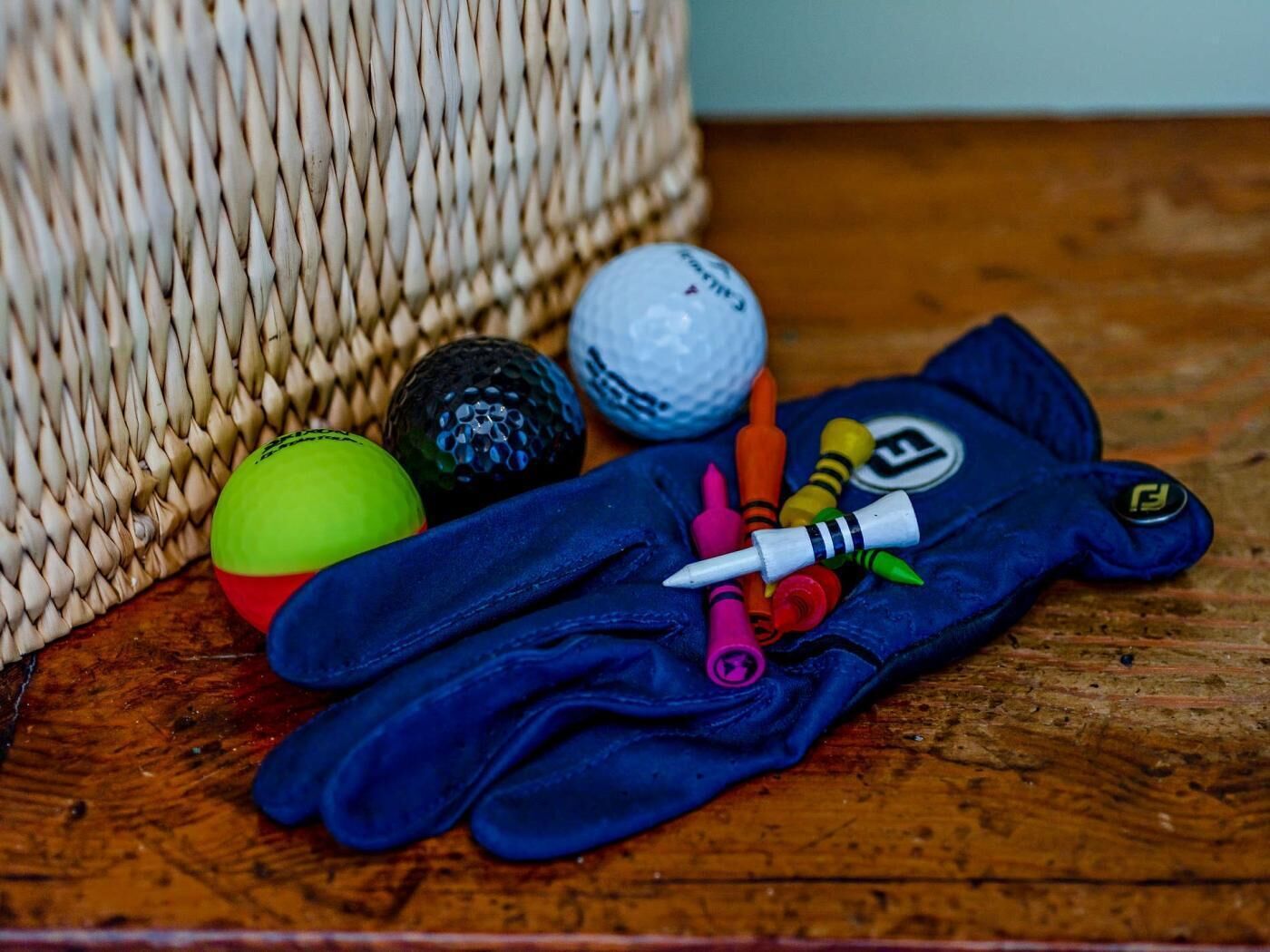 A blue glove, colorful balls, and crayons on a wooden surface.