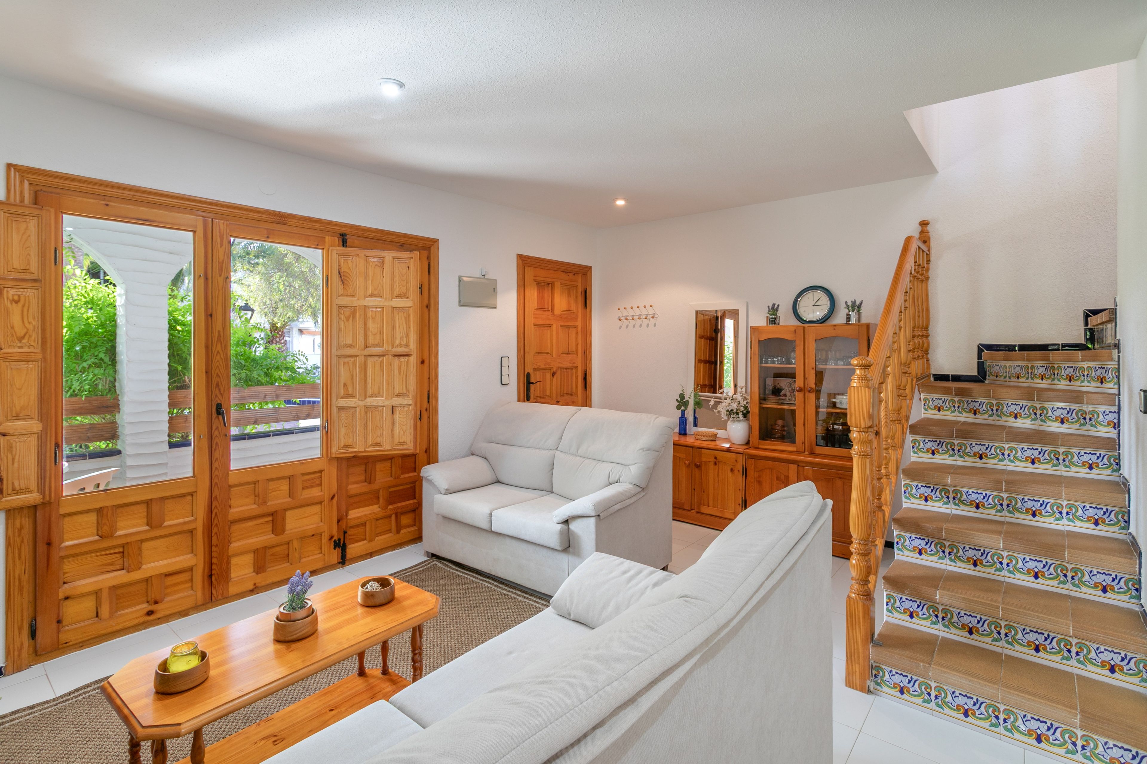 Ein geräumiger Wohnbereich mit einer Couch, einem Holztisch und einer Treppe mit dekorativen Fliesen.