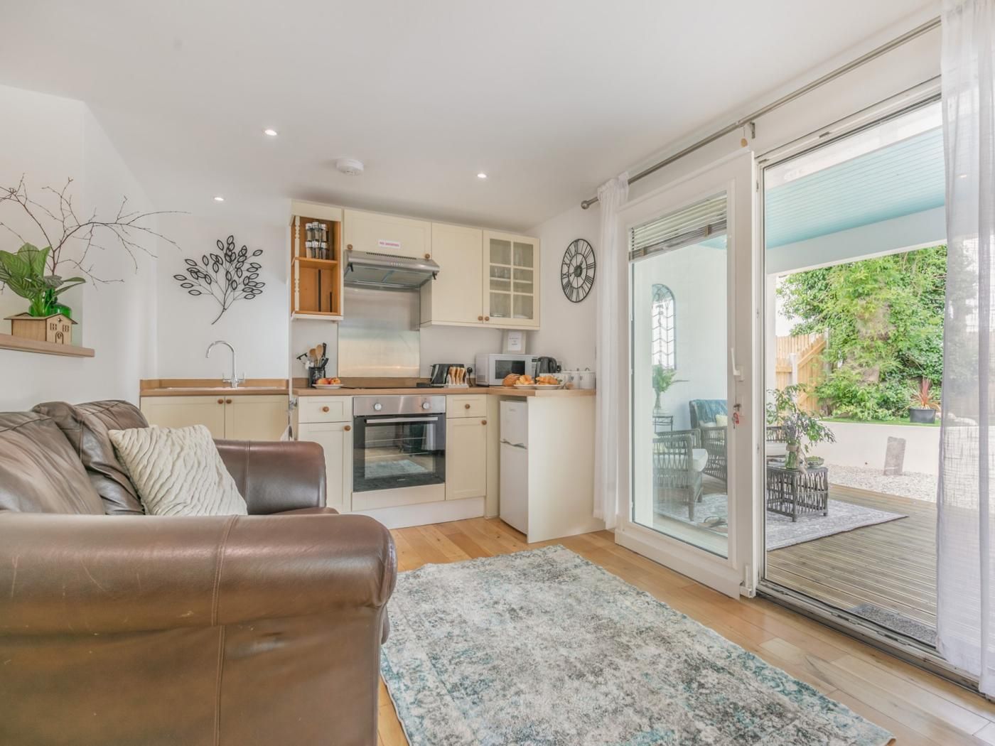 A compact living space with a kitchenette, a dining area, and a sliding glass door leading to an outdoor patio.