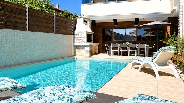 A swimming pool with lounge chairs and a patio area with tables and chairs. - Beautiful home in Pula (Pula)