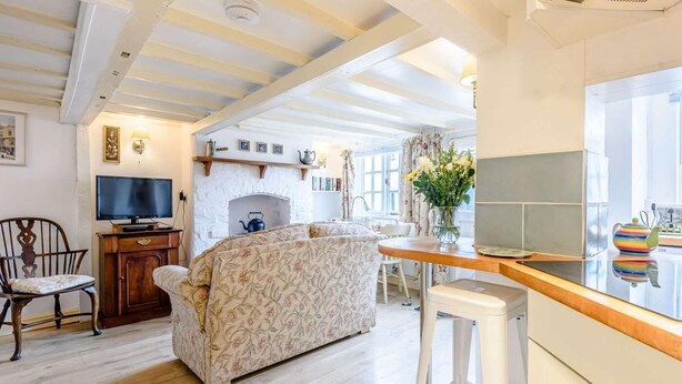 A living room with a sofa, a television, a fireplace, and a kitchen area with a counter and stools.