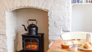 A room with a white brick fireplace, a black wood-burning stove, and a table with bread and butter.