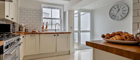 A modern kitchen with white cabinetry, a stainless steel stove, and a large window.