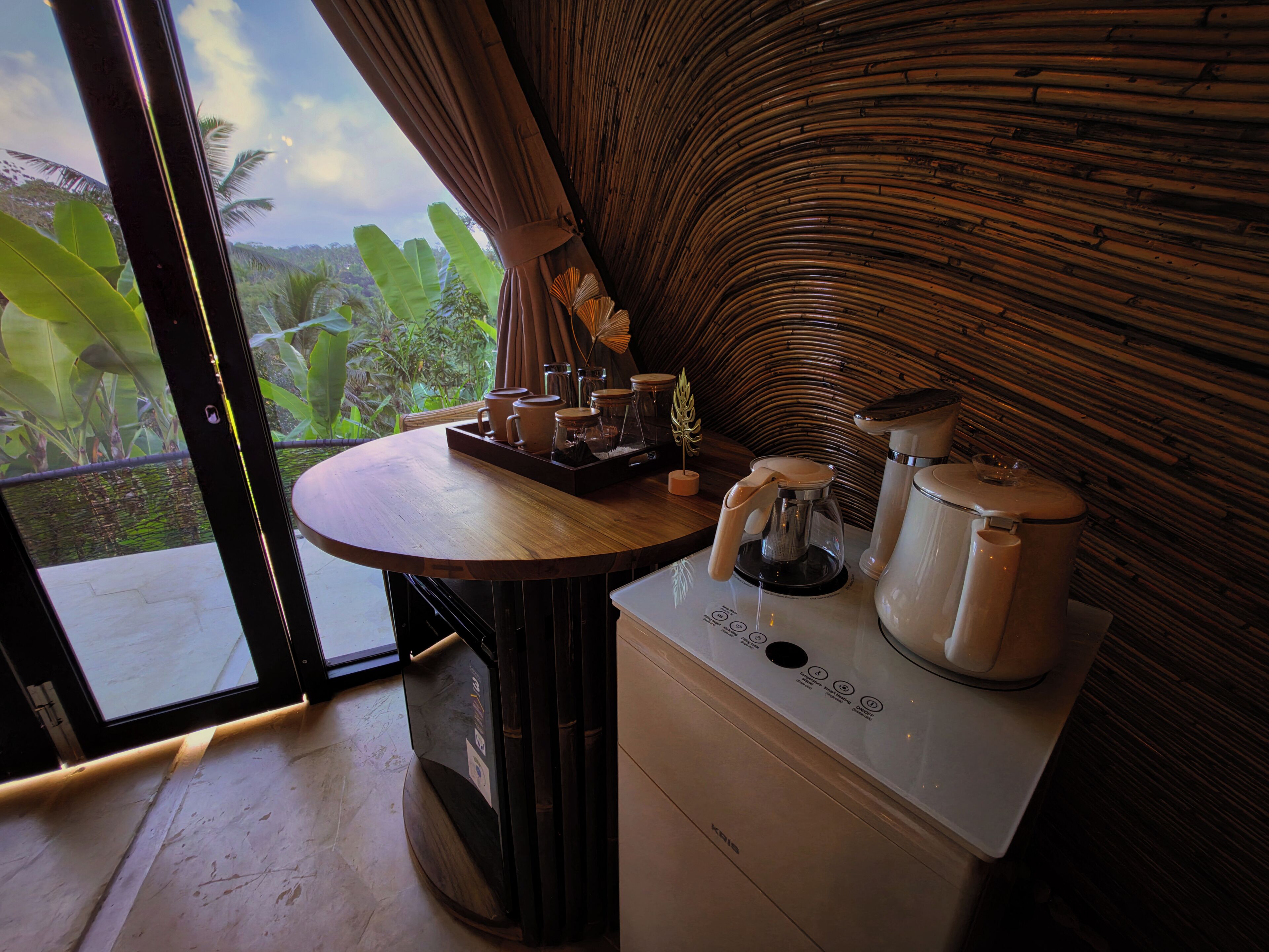 A room with a wooden table, a coffee maker, and a kettle.