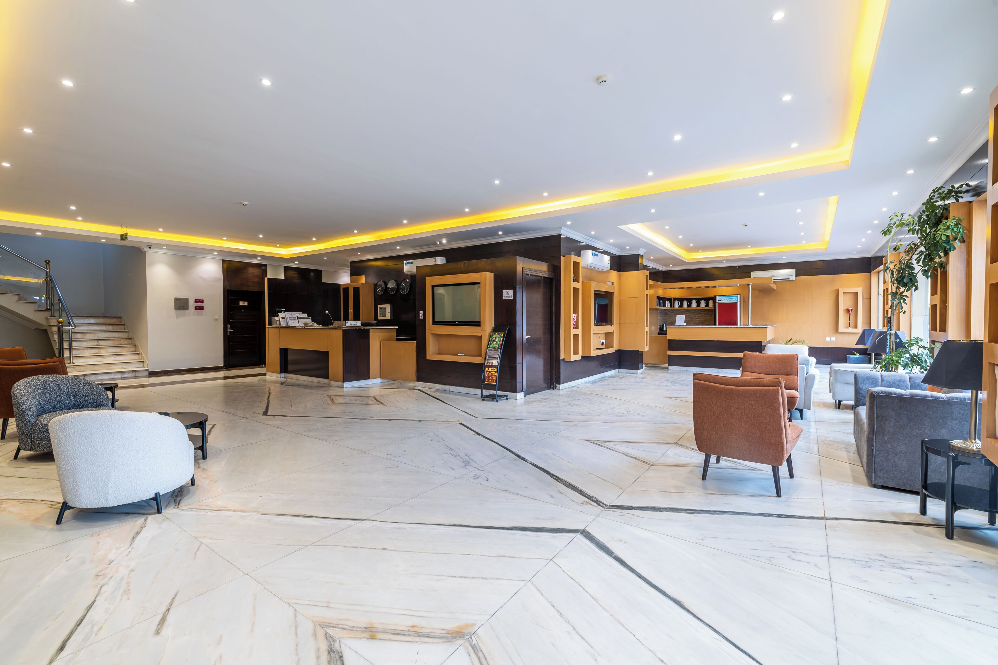 Un hall d’hôtel comprenant un comptoir d’accueil, un espace salon et un escalier.