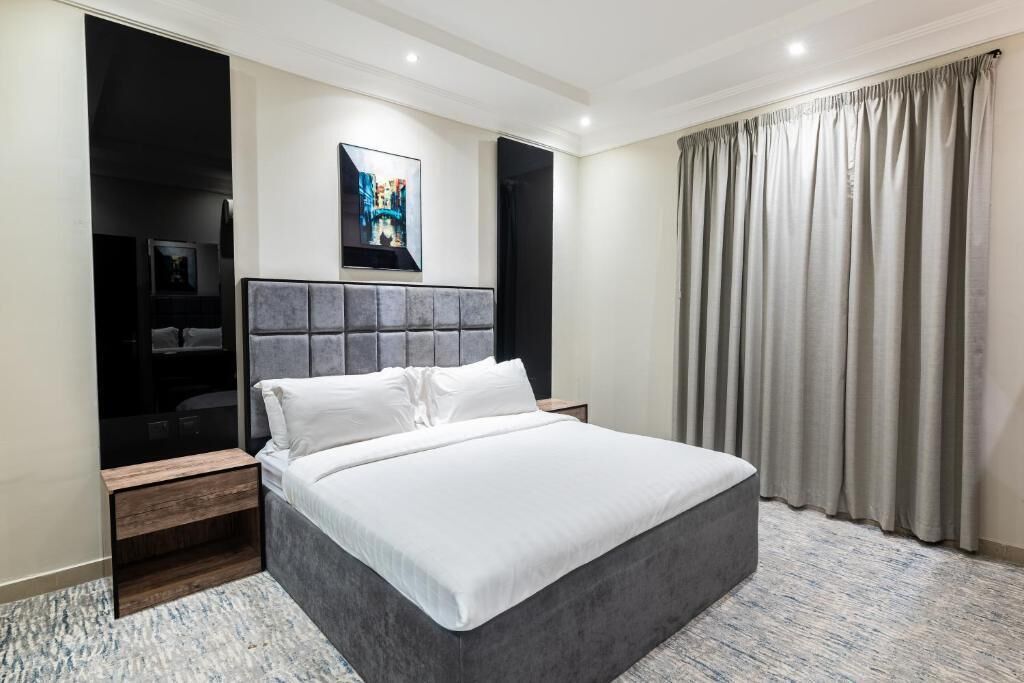 A modern hotel room with a large bed, a flat-screen TV, and a painting on the wall.