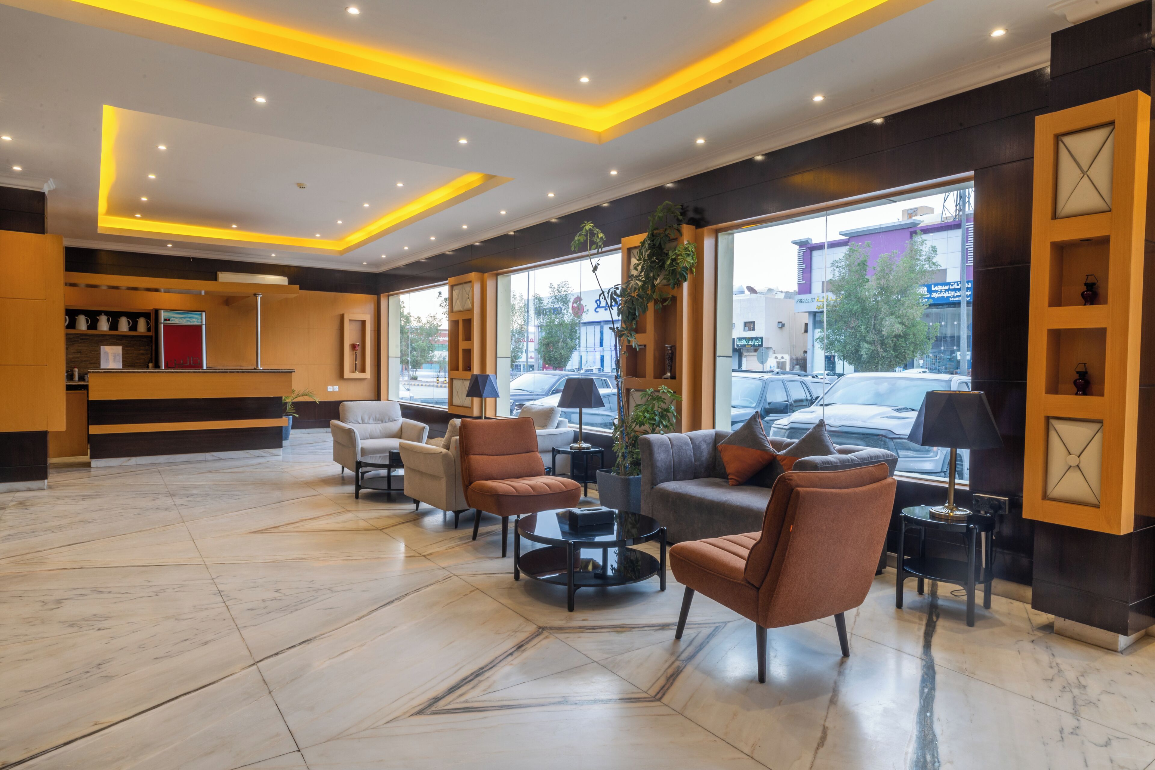 A hotel lobby with a reception desk, seating area, and large windows.