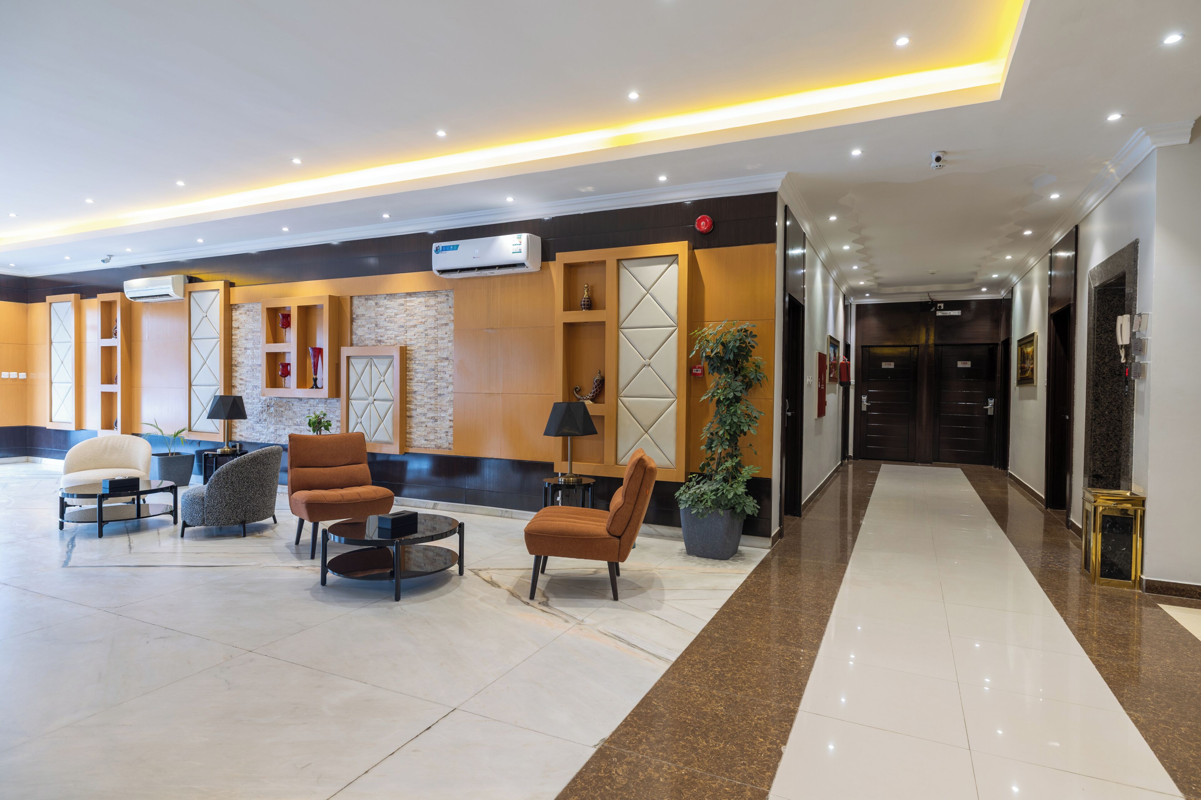 A hotel lobby with seating, a reception desk, and a hallway leading to elevators.