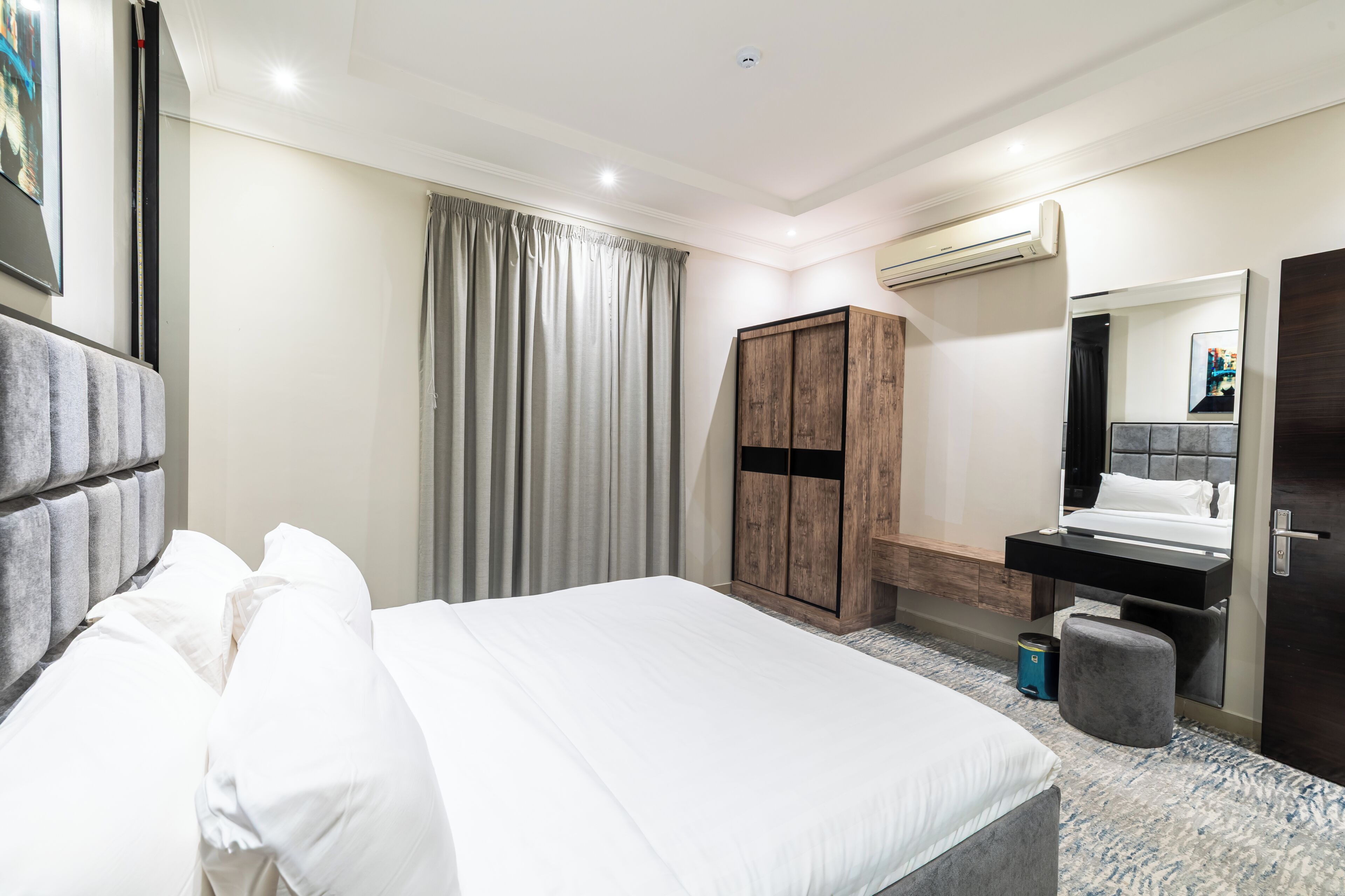 A hotel room with a bed, a wardrobe, a mirror, and a bathroom.