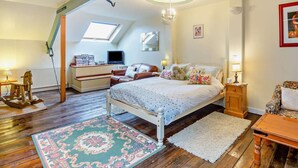 Ein Schlafzimmer mit einem Bett, einem Schreibtisch, einem Schaukelstuhl, einer Chandelüster und einem Oberlicht.