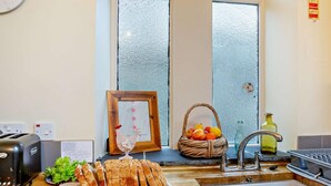 Eine Küche mit Schneidebrett, belegten Brotscheiben, einem Toaster, einer Spüle und einem Fenster mit satiniertem Glas.