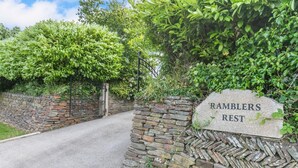 Un mur de pierres avec une pancarte indiquant « HALTE DES RANDONEURS » à l’entrée d’une route.