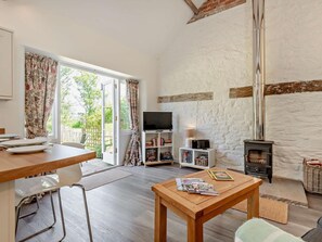 Una sala de estar con televisión, estanterías, chimenea y un comedor con mesa y sillas.