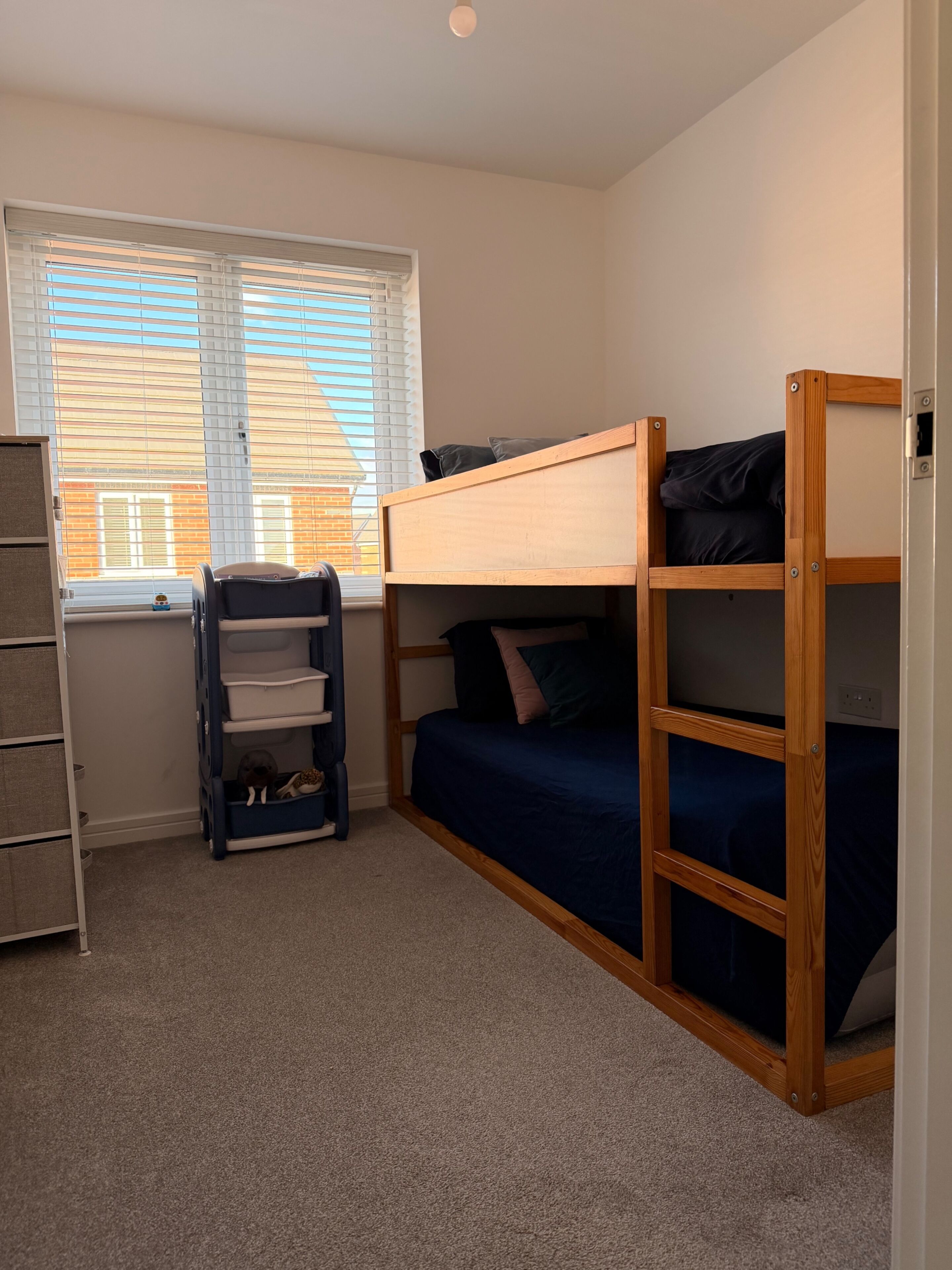 A bunk bed room with a window, a small shelf, and a ladder.
